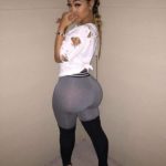 Jeune femme black sexy en jupe grise et chemisier blanc