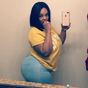 Jeune femme black avec gros cul en pantalon bleu ciel et haut jaune se prend en photo