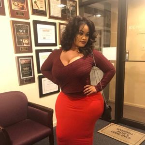 Grosse femme mature noire en jupe rouge et décolleté marron